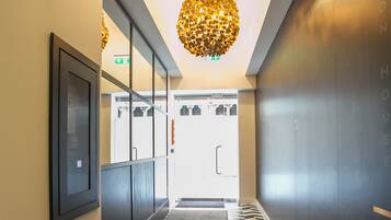 Een hal met een vloer met een geometrisch patroon, een moderne kroonluchter en een deur die naar een kamer leidt.