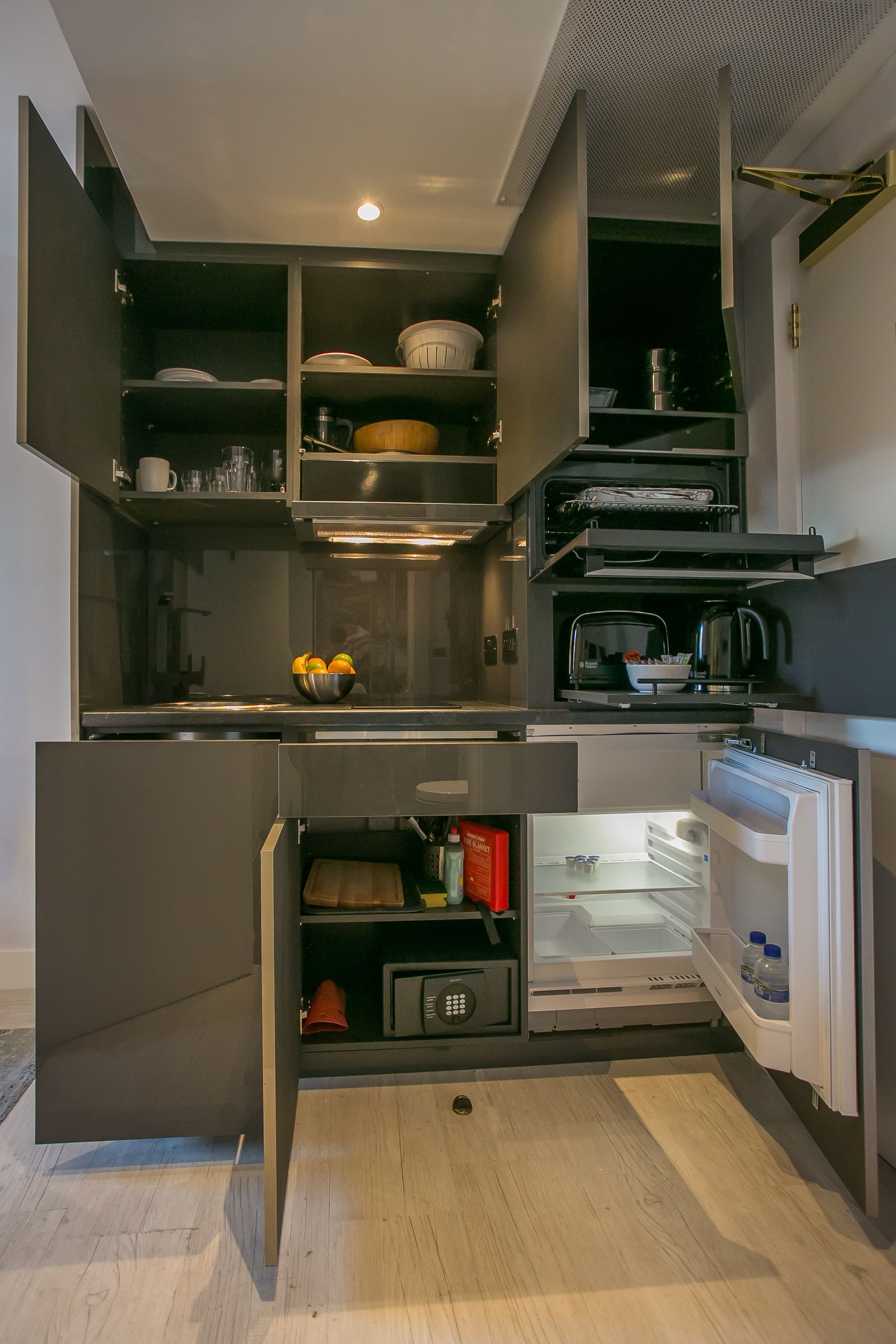 A modern kitchen with built-in appliances, open cabinets, and a microwave.