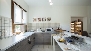 A modern kitchen with a breakfast bar, white countertops, and a wine rack. - B&B Casa Ceruti (Villa Guardia)