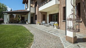 A two-story house with a covered patio, outdoor seating, and a decorative birdcage. - B&B Casa Ceruti (Villa Guardia)