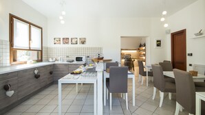 A modern kitchen with white cabinets, a dining table with chairs, and a kitchen island. - B&B Casa Ceruti (Villa Guardia)