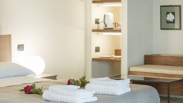 A hotel room with a bed, a wooden bench, and a small table.