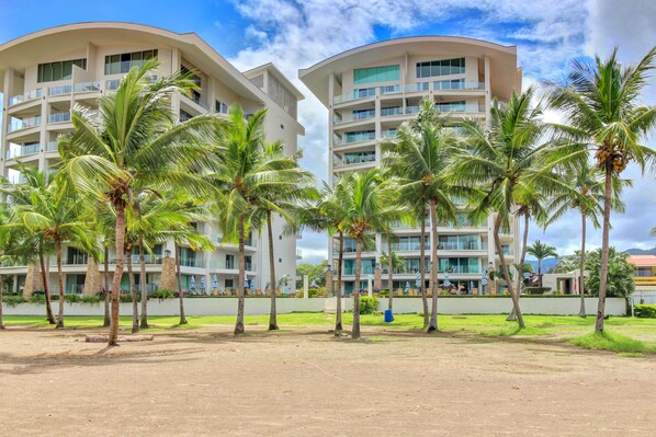 A hotel with multiple floors, balconies, and palm trees.