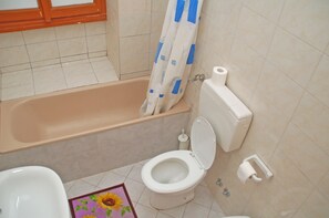 A bathroom with a bathtub, toilet, and a shower curtain. - Cristina's Residence (Rome)