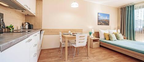 A modern kitchen with a dining area, a bed with a view, and a painting on the wall.