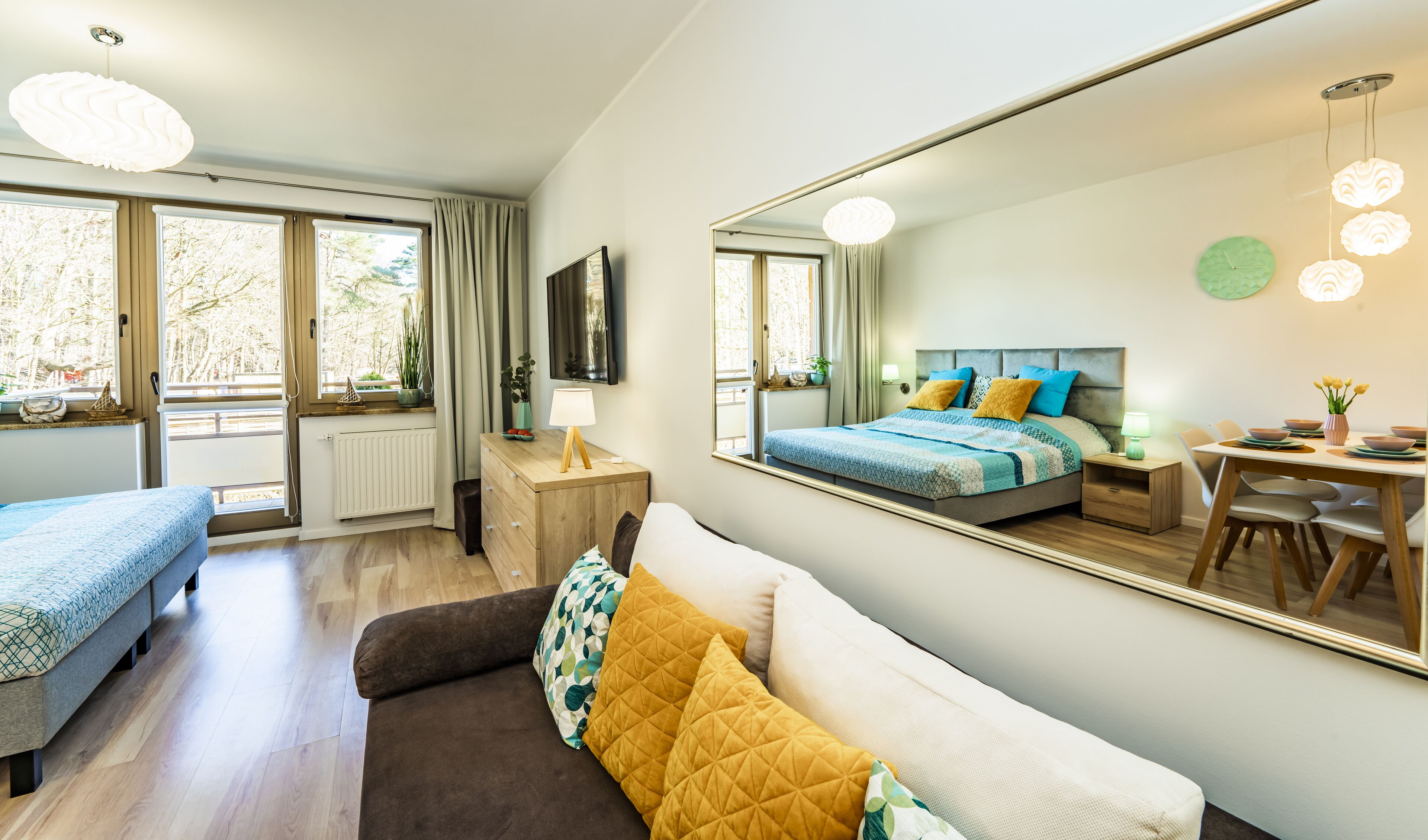 Een moderne slaapkamer met een groot bed, een zithoek met een bank en een eettafel.
