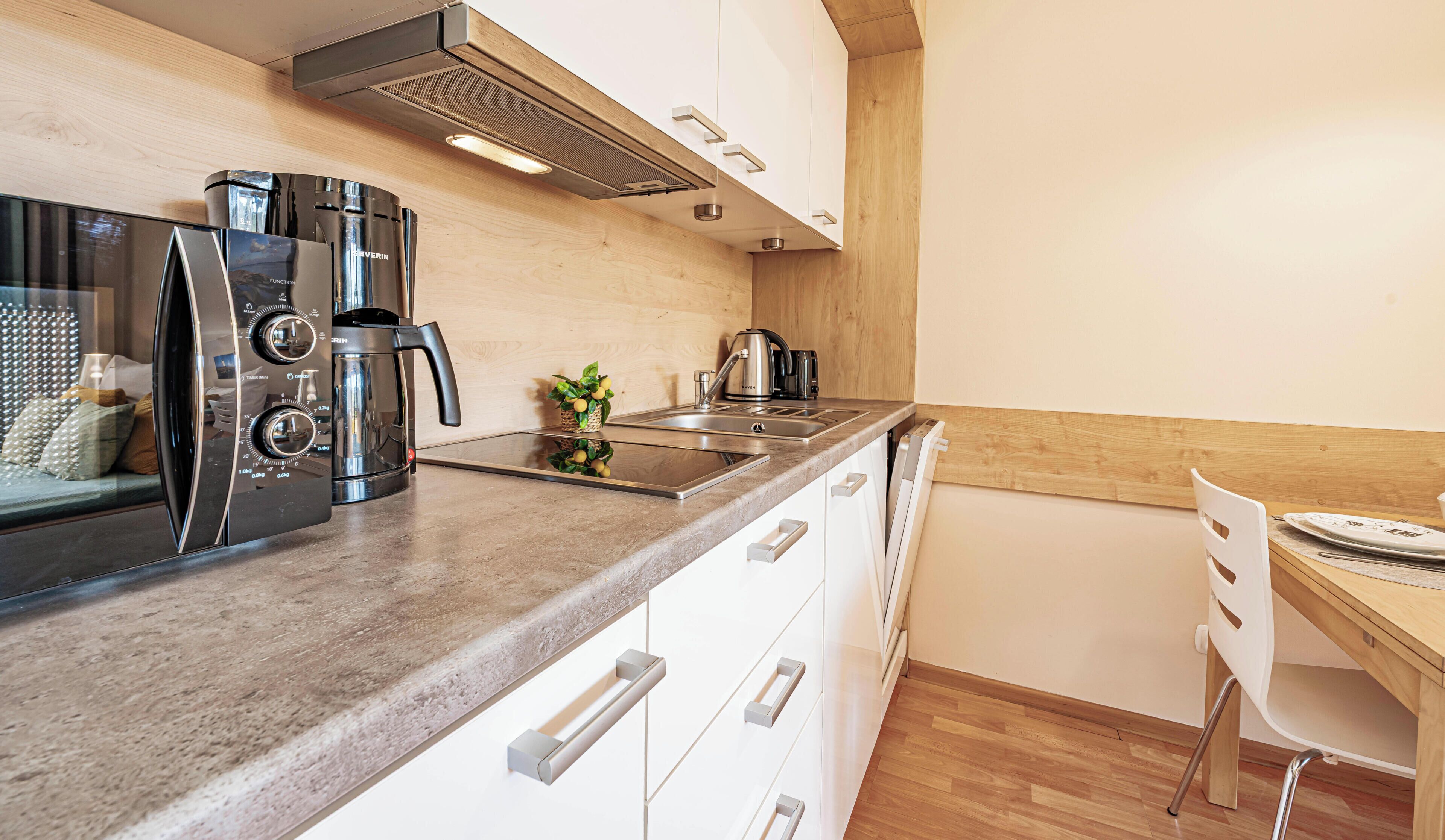 A modern kitchen with a built-in microwave, coffee maker, and kettle.