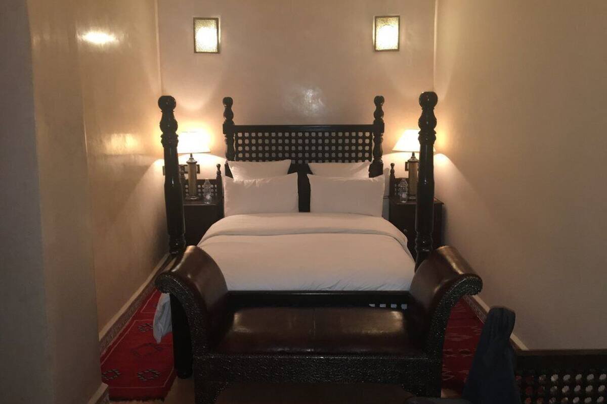 A hotel room with a large bed, two bedside tables, and two wall-mounted lamps.