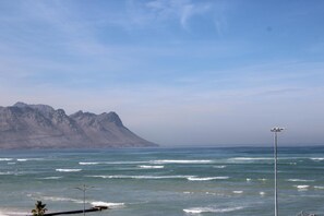 Une vue sur la côte, avec une montagne en arrière-plan, un ciel dégagé et une mer calme.