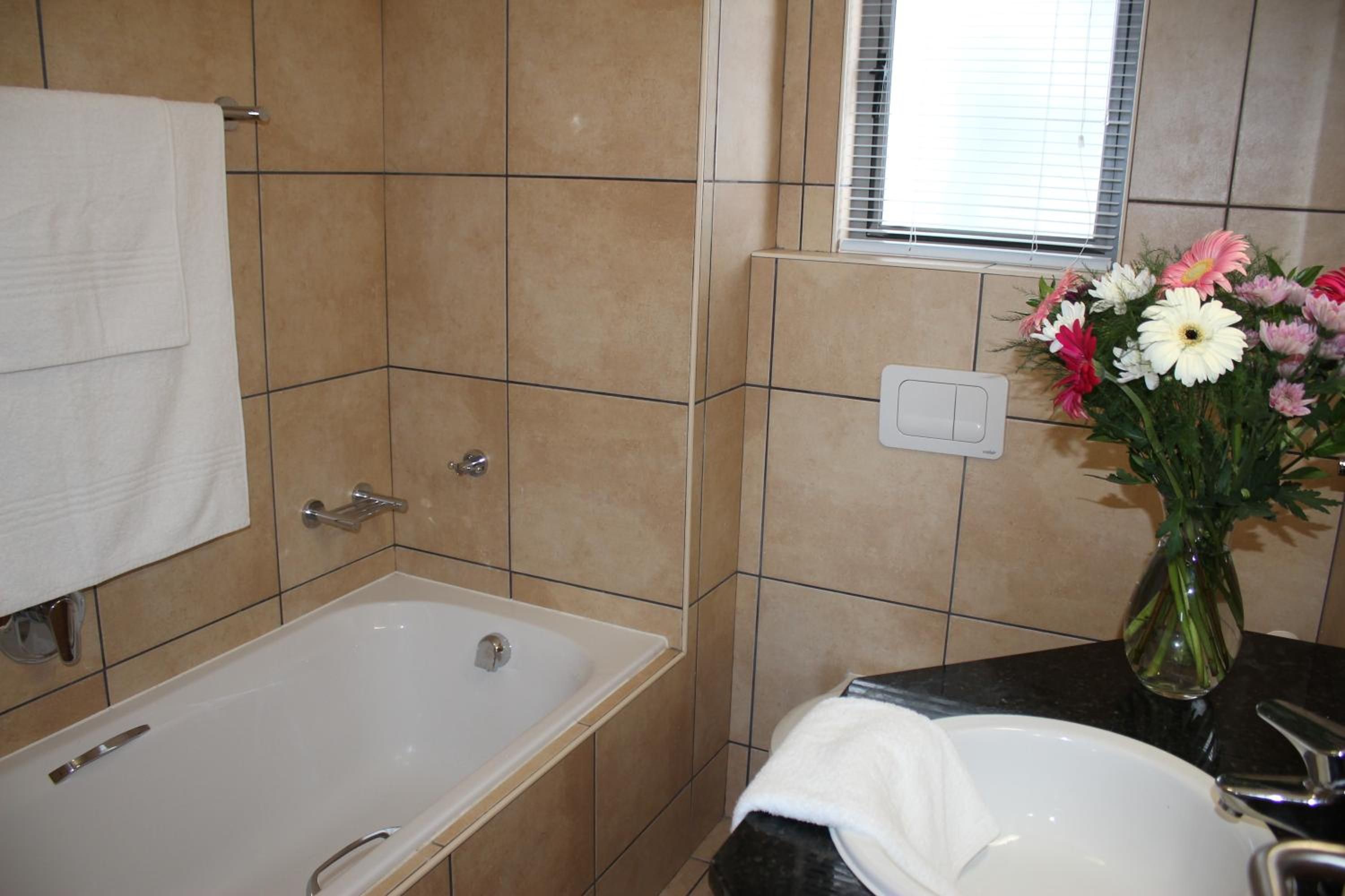 A bathroom with a bathtub, a sink, and a window with blinds.