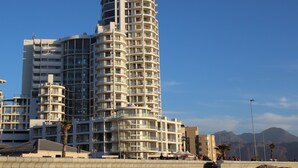 A modern high-rise hotel with multiple balconies, large windows, and a distinctive curved top.