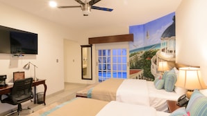 A hotel room with two beds, a desk with a chair, a TV, and a mural of a beach scene.