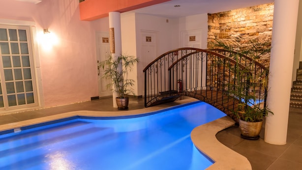 A swimming pool with a curved edge, a staircase with a metal railing, and potted plants.