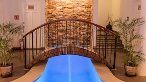 A staircase with a blue carpet, a stone wall, and potted plants.