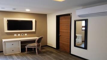 Een slaapkamer met een bed, een bureau, een stoel, een kledingkast en een airconditioning.