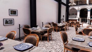 Un comedor con varias mesas y sillas, un suelo estampado y cuadros en las paredes.