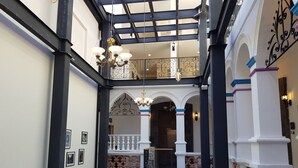 Un patio amplio con techo alto, columnas decoradas y un área de estar con sofás estampados.