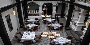 Ein Restaurant mit mehreren gedeckten Tischen, einem gemusterten Boden und aufwendigen Details an der Decke.