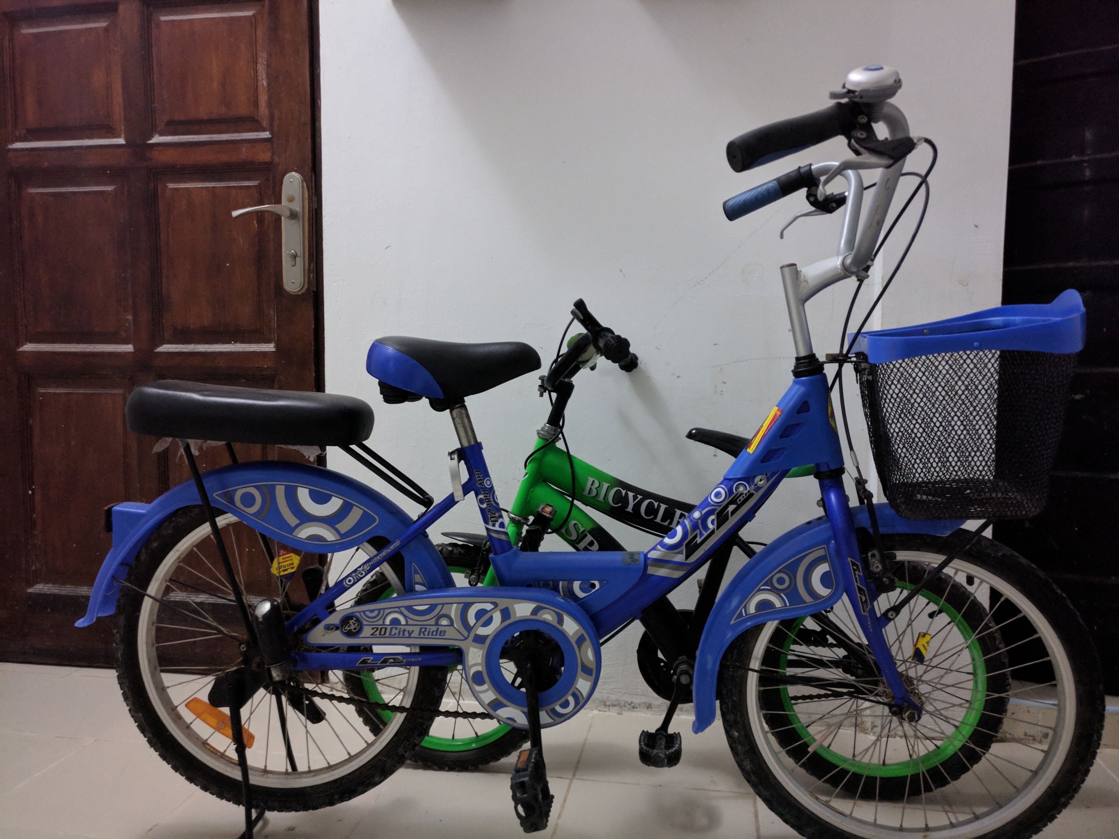 A blue and green bicycle with a basket, parked indoors.