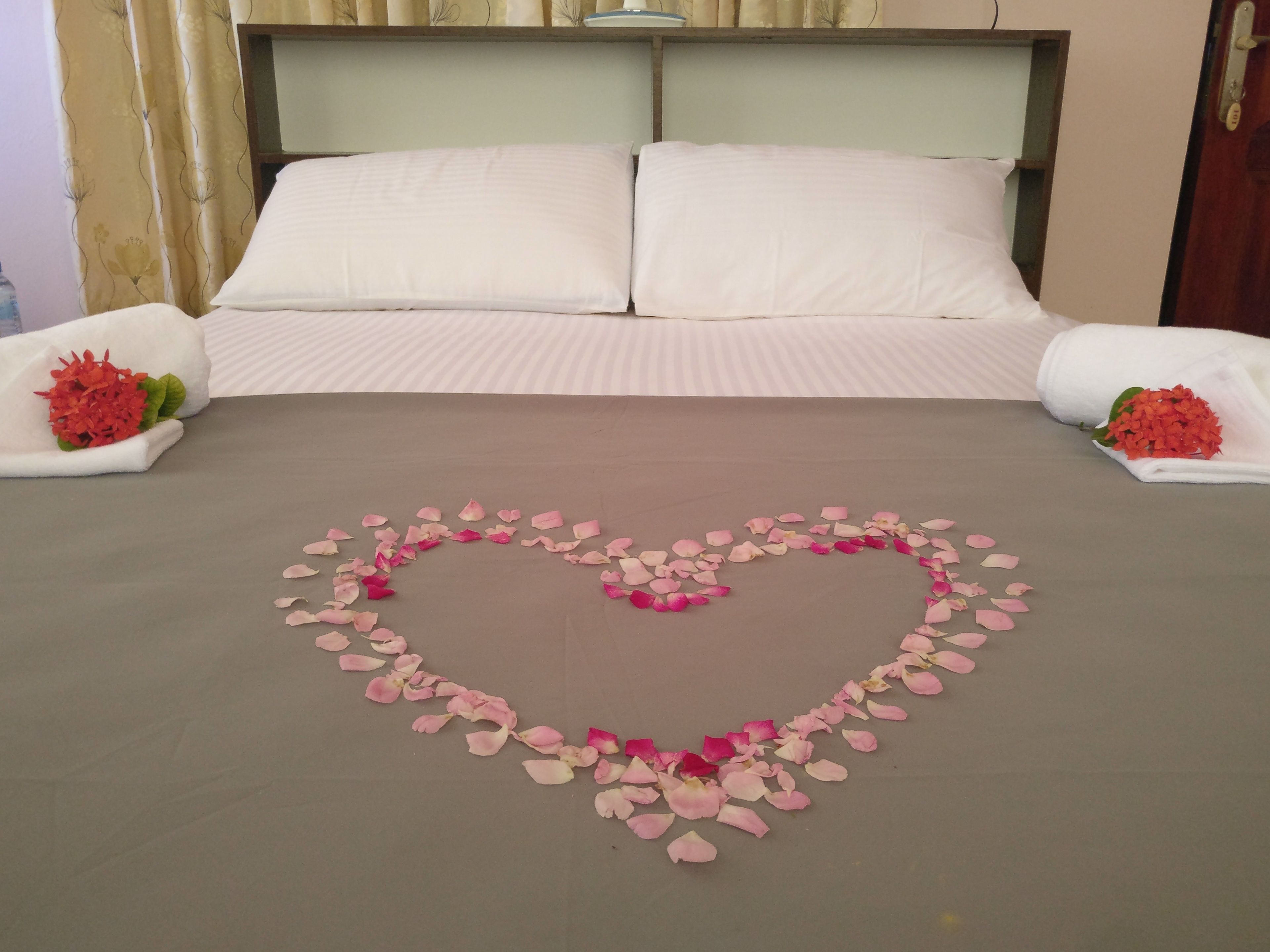 A bed with a heart-shaped arrangement of rose petals in the center.
