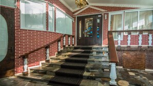 A grand staircase with a red brick wall, a wooden handrail, and a glass balustrade. - Velion Hotel (Kharkiv)