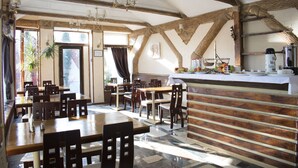 A restaurant with wooden tables and chairs, a bar area, and a view of the outdoors. - Velion Hotel (Kharkiv)