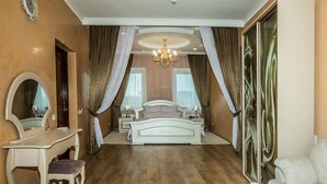 A bedroom with a large bed, a vanity with a mirror, and a chandelier. - Velion Hotel (Kharkiv)