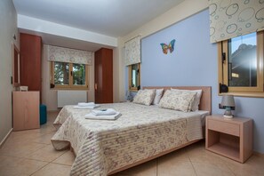 A bedroom with a large bed, a nightstand, a dresser, and a window with a butterfly decoration. - Palladio Luxury Villa (Rethymno)