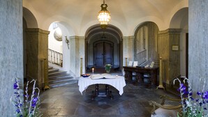 A grand hallway with a marble floor, a staircase, and a table with a book and candle. - Husby Säteri (Soderkoping)