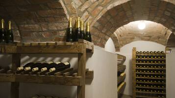 Una bodega con estanterías de madera llenas de botellas y una pared de ladrillo.