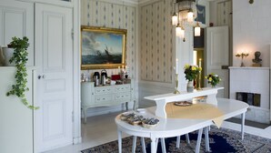 A dining area with a white table, a chandelier, and a fireplace. - Husby Säteri (Soderkoping)