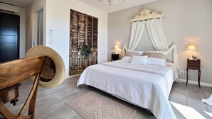Een slaapkamer met een groot bed, een kroonluchter, een houten hoofdbord, een nachtkastje en een decoratief wandpaneel.