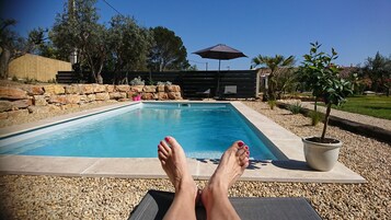 Una piscina al aire libre de temporada, sombrillas