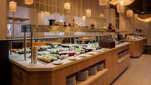 A buffet with various food items and a Buddha statue. - RIU Helios Bay – All Inclusive (Obzor)