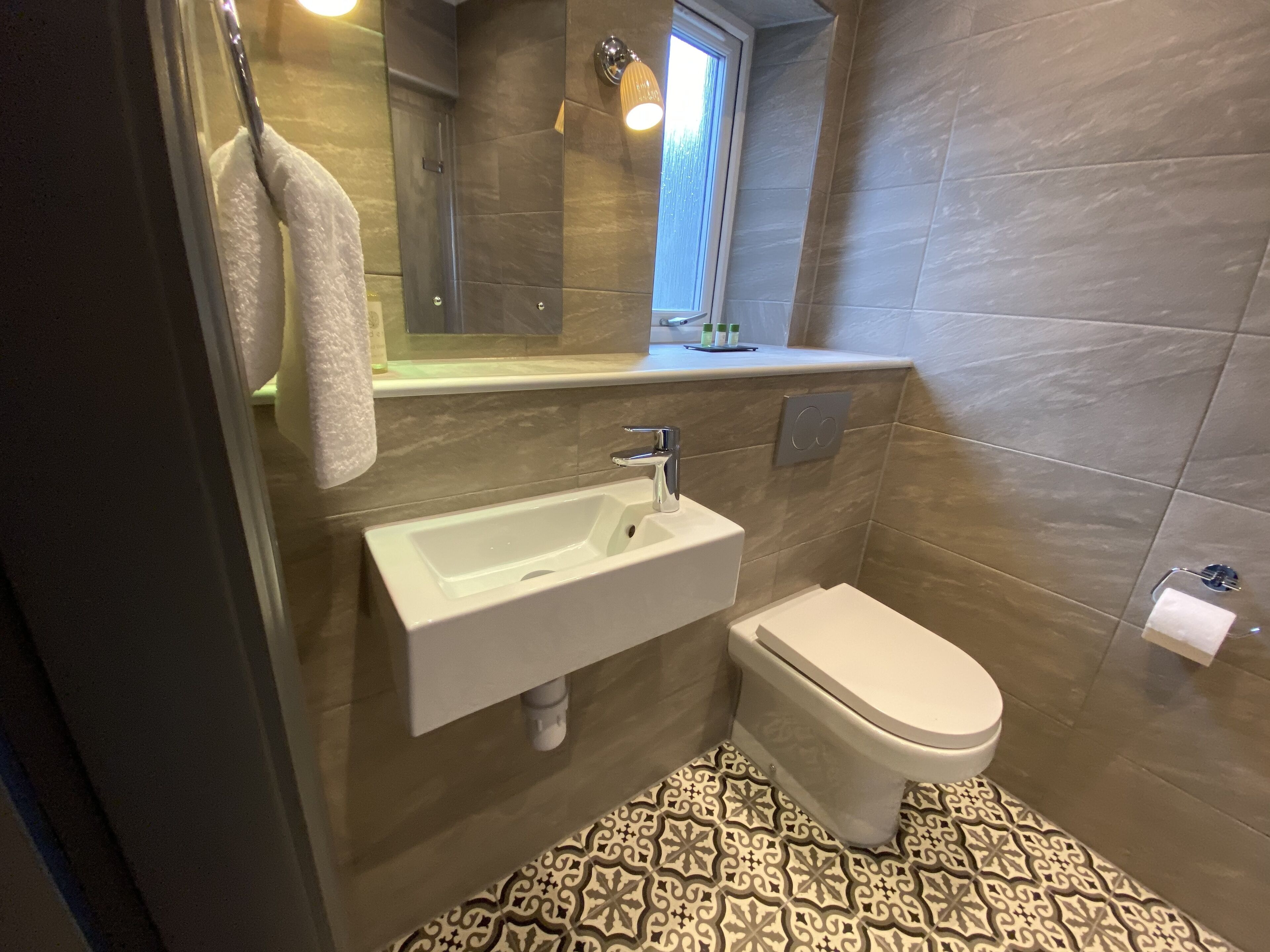 A bathroom with a white sink, a toilet, and a patterned floor.