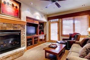 Una sala de estar con chimenea, televisor y asientos cómodos.