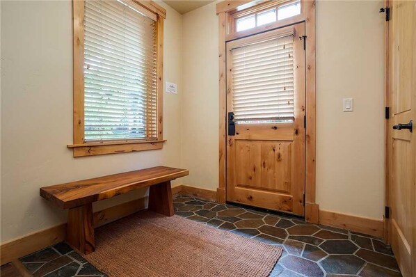 A wooden bench, a door, and a window with blinds.