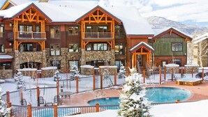 A multi-story lodge with a pool and outdoor seating, surrounded by snow. - 6115 Bear Lodge, Trappeur's Crossing Apartment 1 (Steamboat Springs)