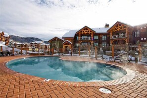 Un’area piscina con idromassaggio, casette in legno e montagne sullo sfondo.