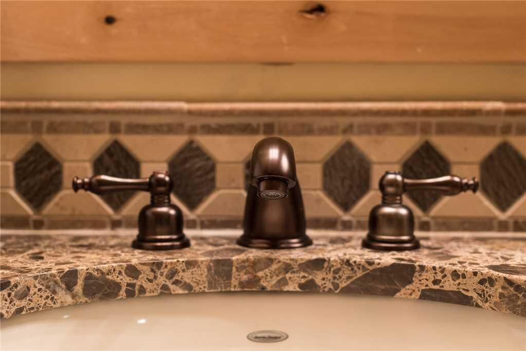 A bathroom with a marble countertop and three wall-mounted faucets.