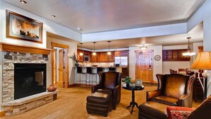 A spacious living room with a fireplace, leather armchairs, and a dining area with a lamp.