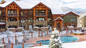 A multi-story lodge with a pool area, stone facade, and wooden balconies.