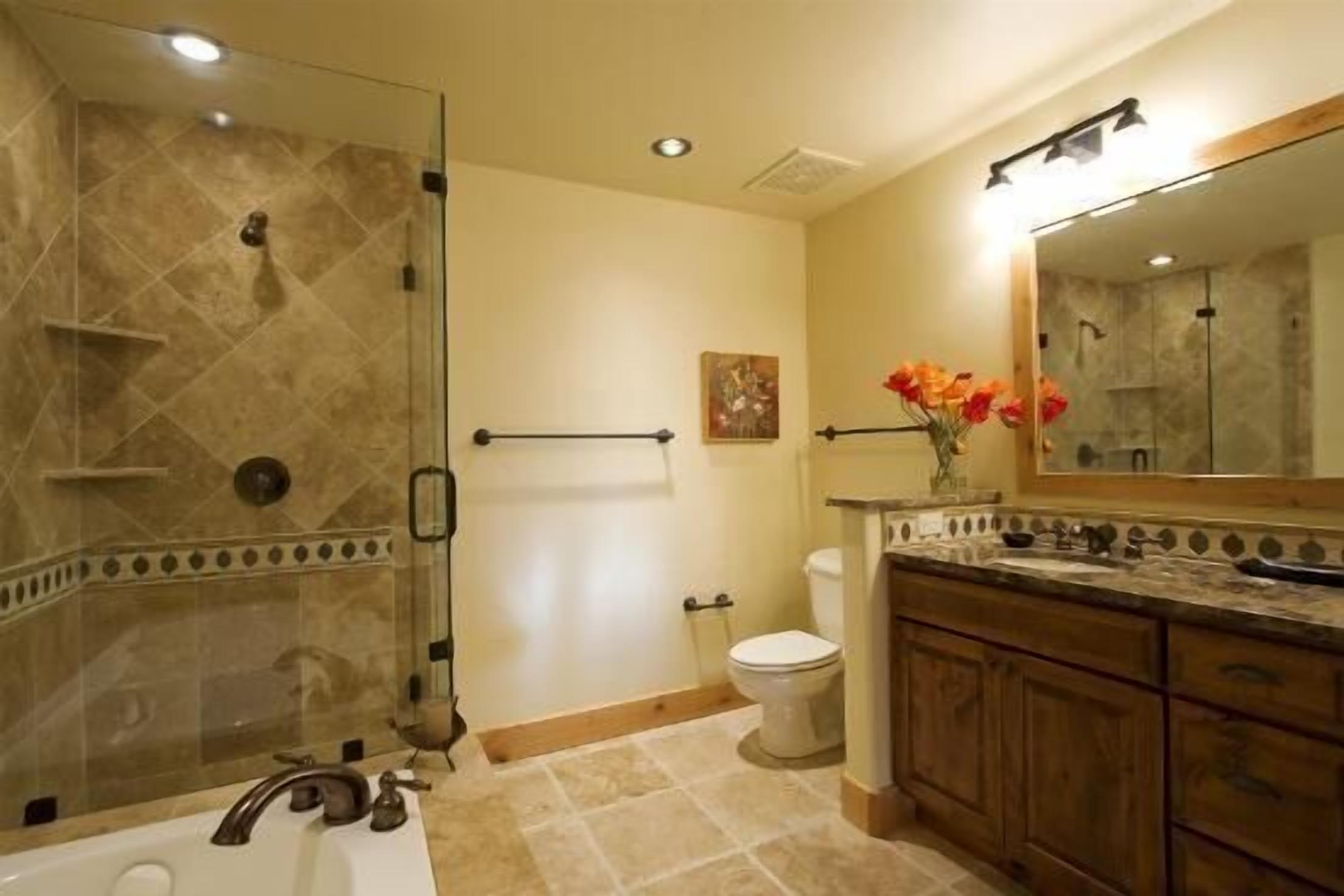 A bathroom with a glass-enclosed shower, a white toilet, a vanity with a mirror, and a bathtub.