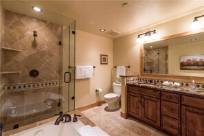 A bathroom with a glass-enclosed shower, a large mirror, wooden cabinets, and a bathtub. - 6307 Bear Lodge, Trappeur's Crossing Apartment 3 (Steamboat Springs)