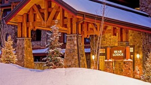 Un chalet à la façade en pierre, avec des poutres en bois et une enseigne indiquant « Bear Lodge ».