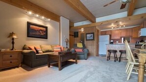 A cozy living room with a sofa, coffee table, and a dining area with wooden chairs and a table. - 218 Storm Meadows Club B Apartment 1 (Steamboat Springs)