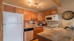 A kitchen with wooden cabinets, a white refrigerator, a microwave, a dishwasher, and a stove. - 218 Storm Meadows Club B Apartment 1 (Steamboat Springs)