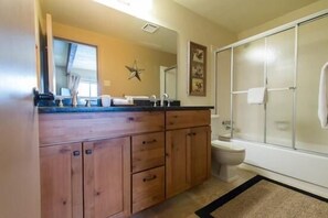 Une salle de bain avec des meubles en bois, des toilettes blanches et une cabine de douche en verre.