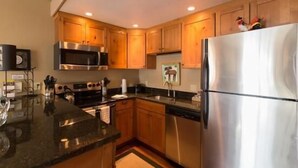 Una cocina moderna con armarios de madera, electrodomésticos de acero inoxidable y encimera de granito.