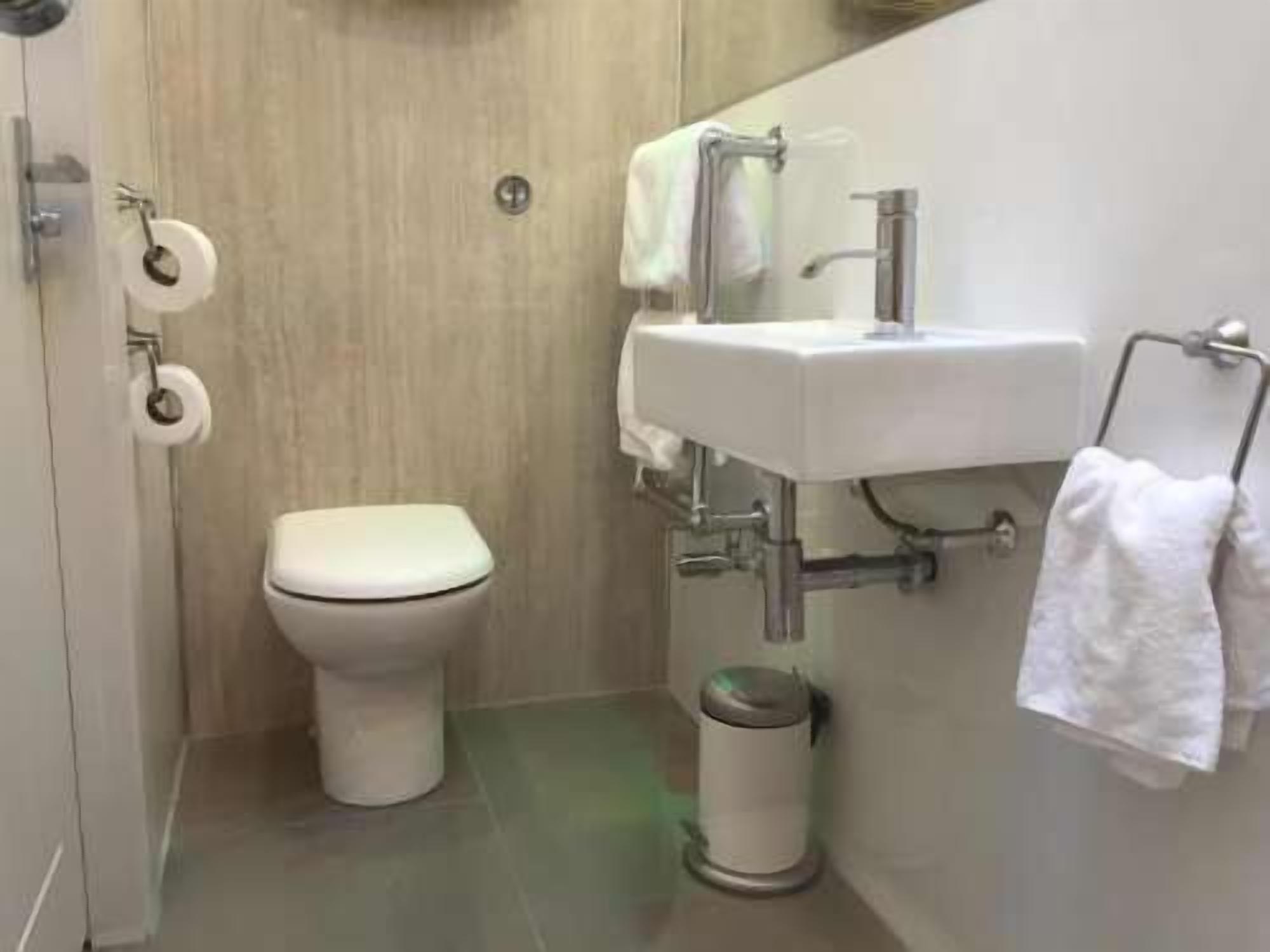 A small, modern bathroom with a toilet, sink, and trash can.